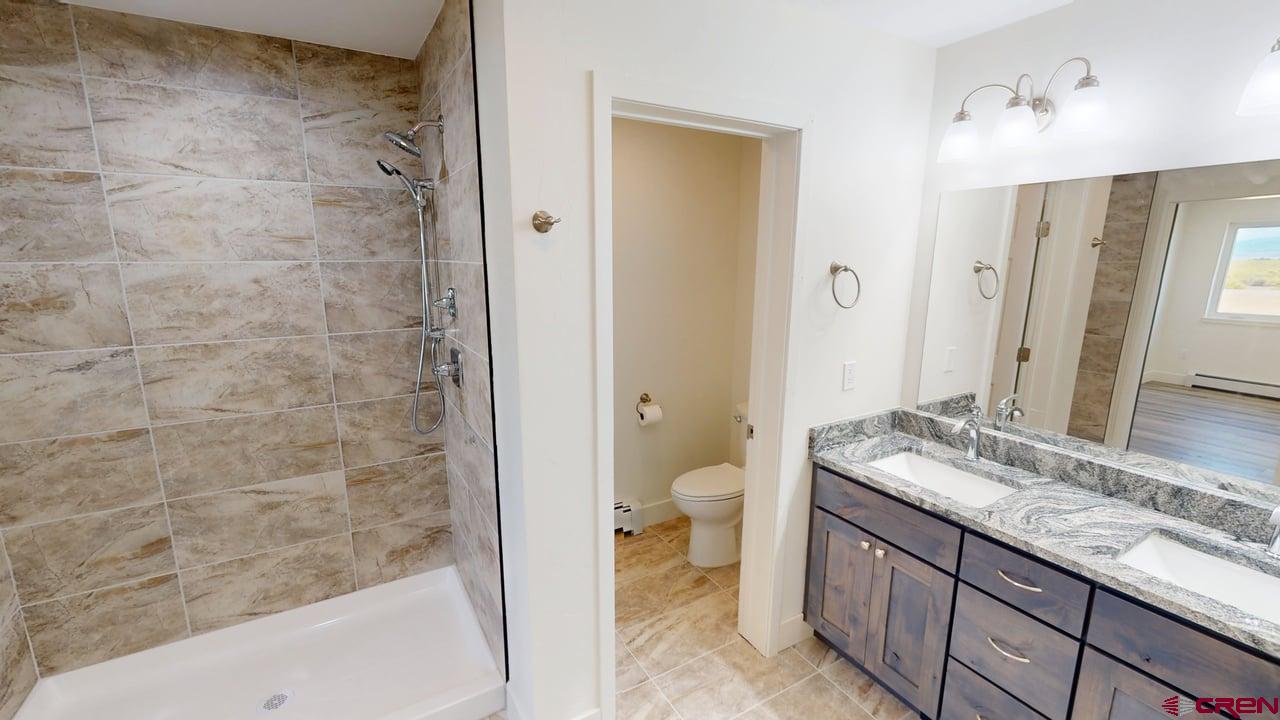 8714 Ridgetop Drive Alamosa, CO 81101 - Photo 11 of 18 a bathroom with a granite countertop sink a toilet and shower