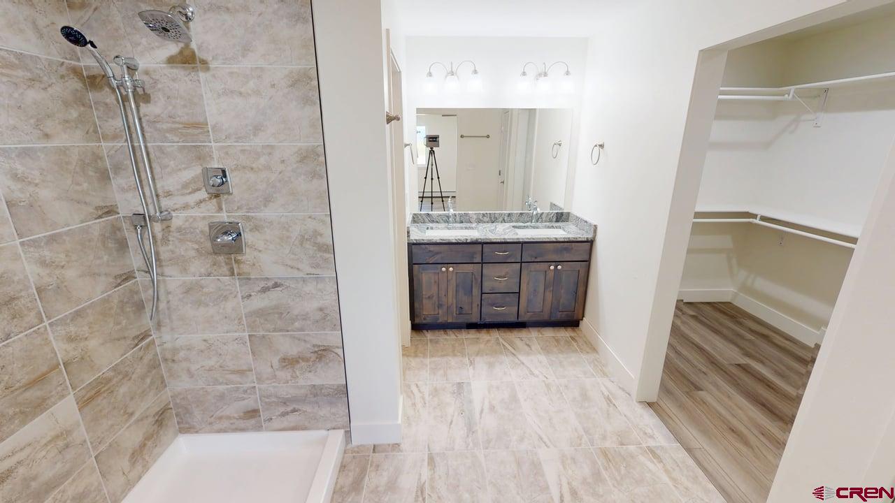 8714 Ridgetop Drive Alamosa, CO 81101 - Photo 12 of 18 a bathroom with a granite countertop sink a mirror and shower