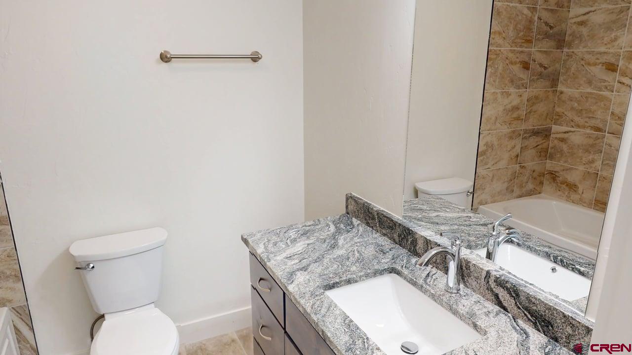8714 Ridgetop Drive Alamosa, CO 81101 - Photo 15 of 18 a bathroom with a granite countertop toilet and a sink
