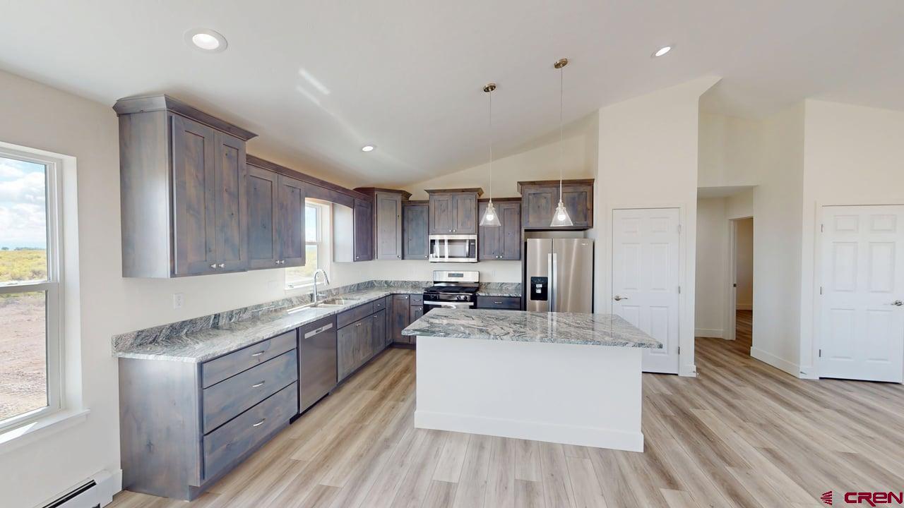8714 Ridgetop Drive Alamosa, CO 81101 - Photo 9 of 18 a large kitchen with stainless steel appliances granite countertop a lot of counter space and wooden floors