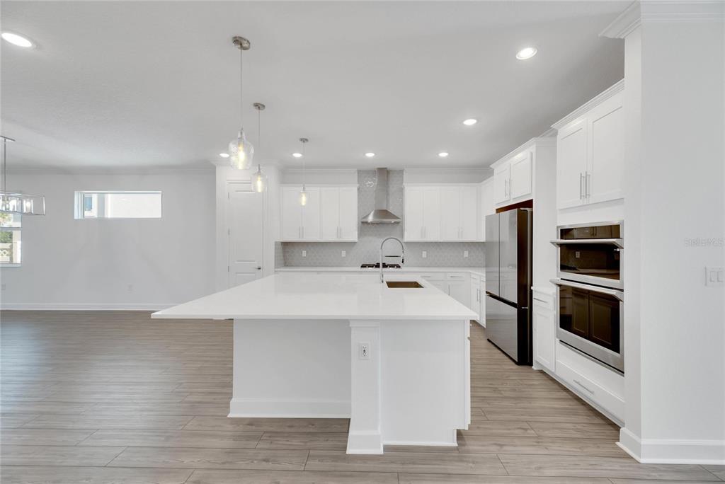 923 Signet Drive Apollo Beach, FL 33572 - Photo 21 of 84 a large white kitchen with kitchen island a sink a stove and a refrigerator