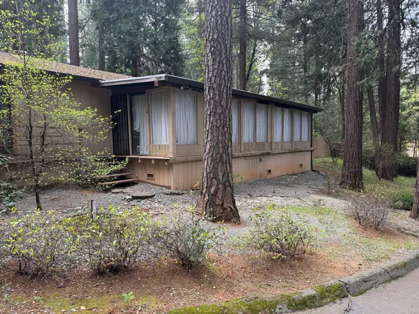 a backyard of a house with large trees and wooden fence