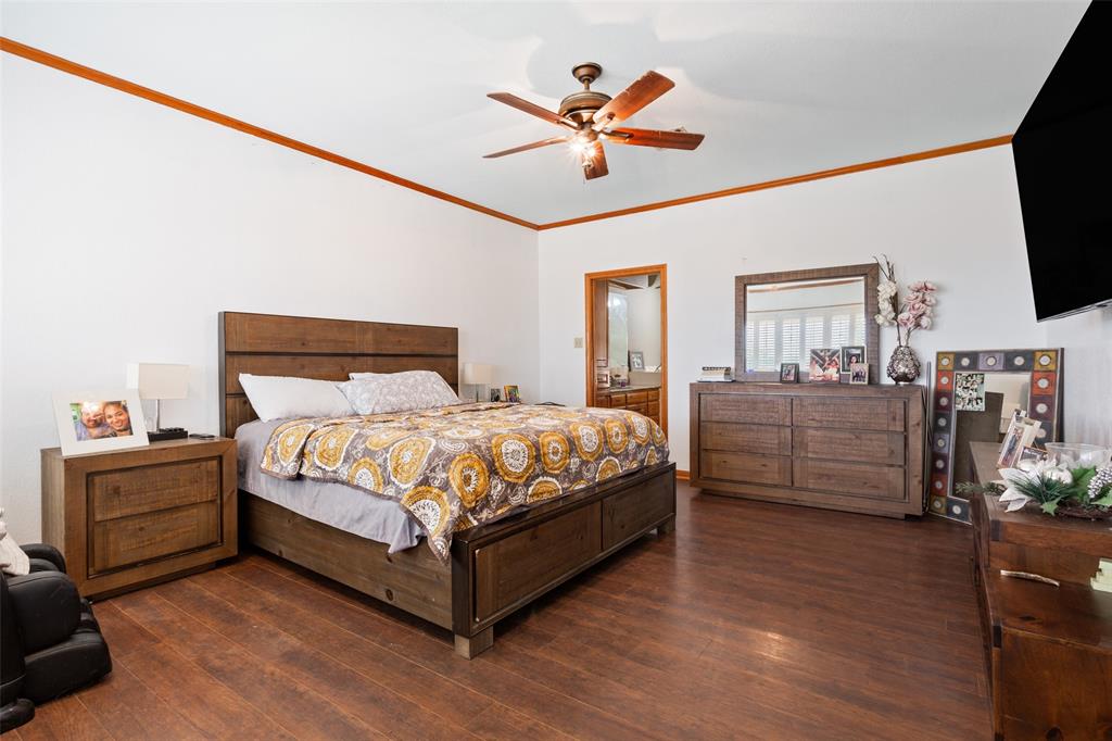 564 Sam Bass Road McGregor, TX 76657 - Photo 14 of 37 Spacious bedroom featuring wood-finish flooring and white walls with a contrasting wood trim accent