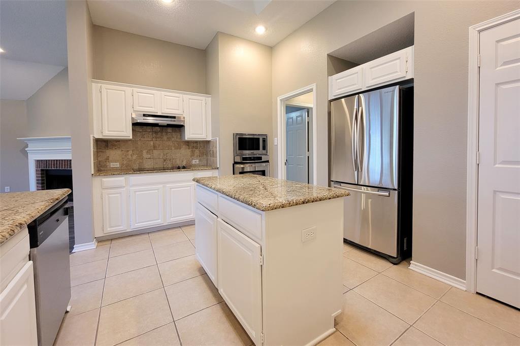 1604 Knoll Ridge Circle Corinth, TX 76210 - Photo 17 of 37 Kitchen featuring a central island with a granite-style countertop, white cabinetry, and stainless steel appliances