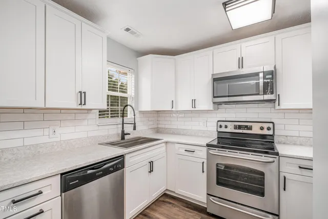 a kitchen with granite countertop a sink stove and microwave