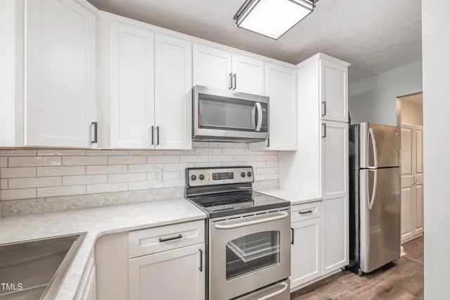 a kitchen with stainless steel appliances white cabinets and a refrigerator