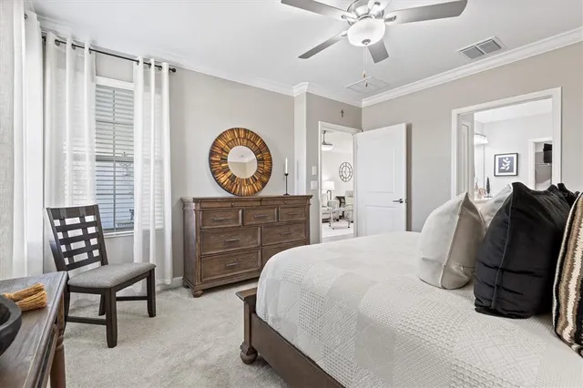 a spacious bedroom with a bed a dresser and a chandelier