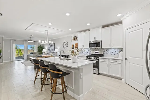 a kitchen with stainless steel appliances kitchen island granite countertop a stove a sink a dining table and chairs