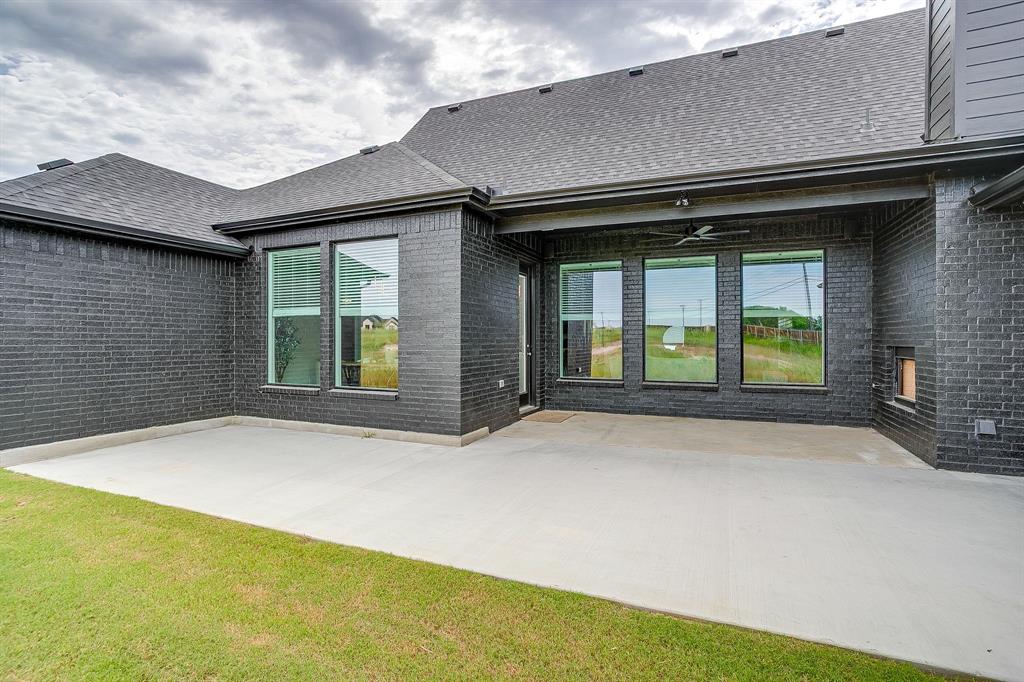 4511 Matador Rnch Road Waxahachie, TX 75165 - Photo 33 of 36 Exterior featuring dark brick facade, a covered patio with an installed ceiling fan, a concrete patio surface, and multiple large windows