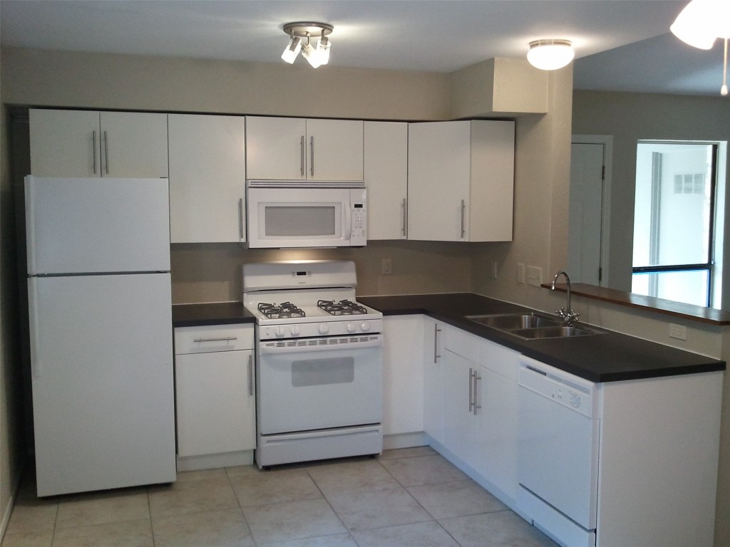 5212 Downs Drive Austin, TX 78721 - Photo 3 of 16 a kitchen with a sink and a refrigerator