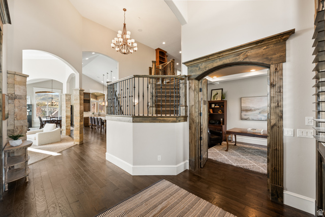 1205 North Elk Rdg Lane, Unit 202 Alpine, UT 84004 - Photo 10 of 88 Spacious foyer with dark wood-finish flooring, a grand staircase featuring wood and iron railings, and a vaulted ceiling with a chandelier