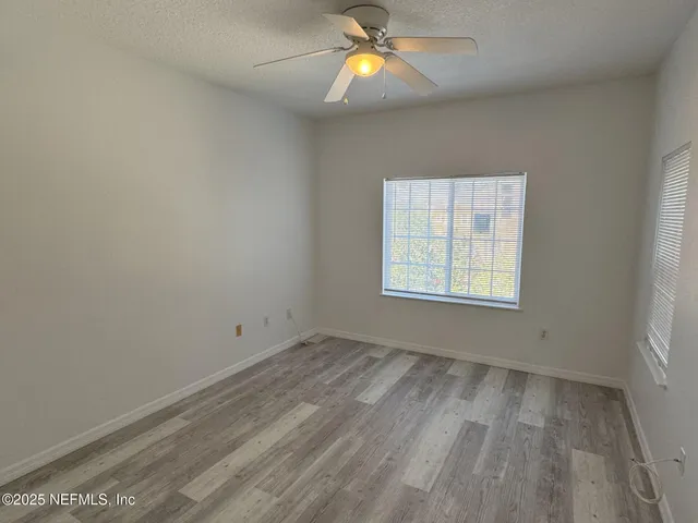 an empty room with windows and fan