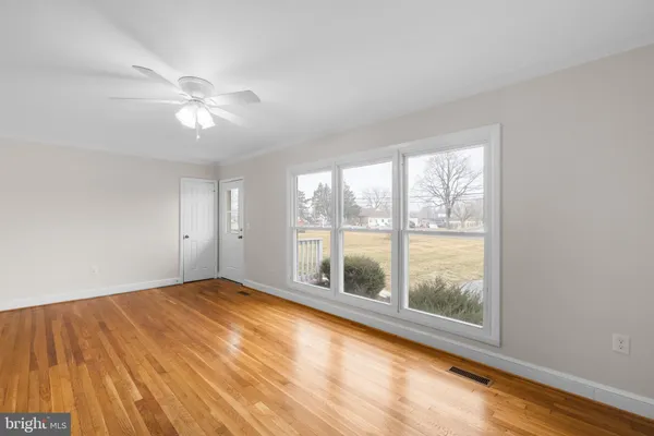 a view of empty room with wooden floor and fan