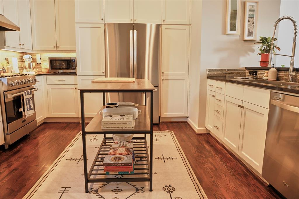4026 Travis Street, Unit E Dallas, TX 75204 - Photo 9 of 19 a kitchen with stainless steel appliances a stove a sink and white cabinets with wooden floor