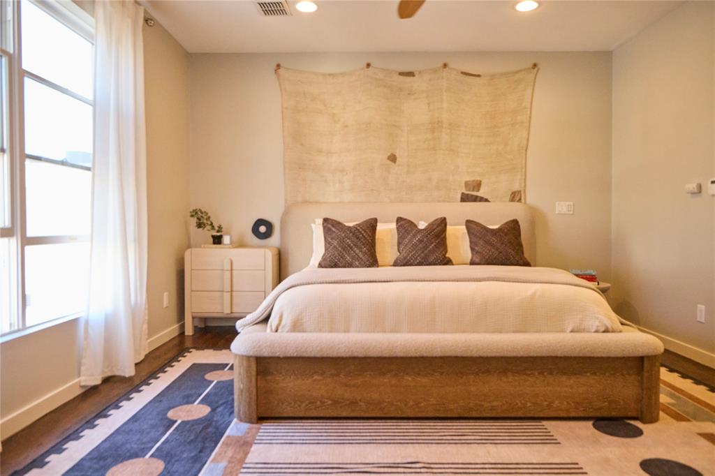 4026 Travis Street, Unit E Dallas, TX 75204 - Photo 10 of 19 a bedroom with a bed and wooden floor