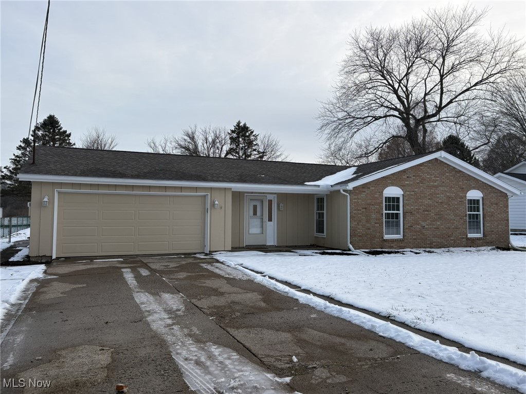 Ranch-style home featuring brick siding, a garage, driveway, a porch, and roof with shingles