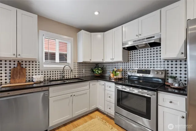 a kitchen with granite countertop white cabinets stainless steel appliances and sink