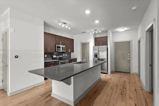 a large kitchen with stainless steel appliances a large counter top a stove and a refrigerator