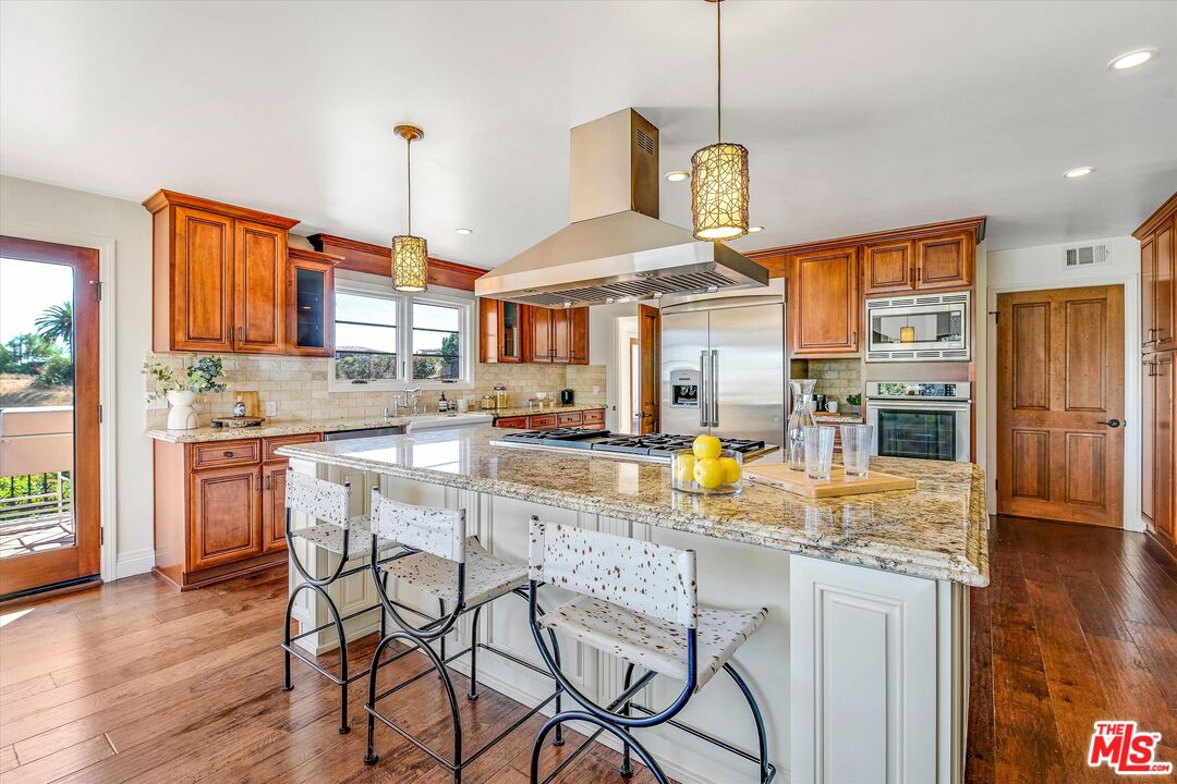 1405 Mayapan Road La Habra Heights, CA 90631 - Photo 17 of 54 a kitchen with stainless steel appliances granite countertop a stove top oven a refrigerator a sink and a dining table with wooden floor