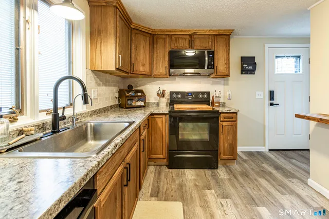 a kitchen with kitchen island granite countertop a sink stainless steel appliances and cabinets