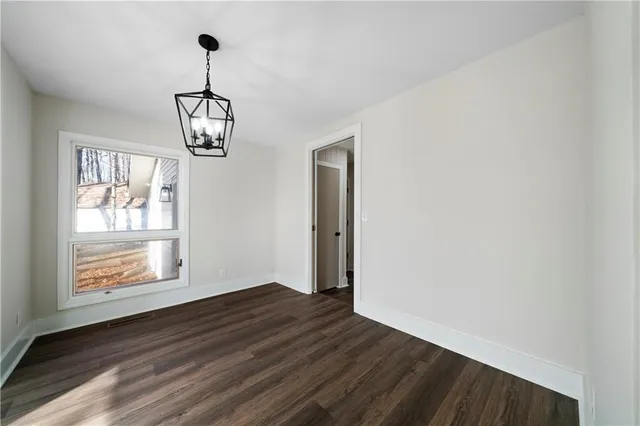a view of empty room with wooden floor and window