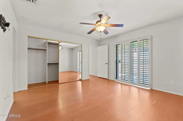 an empty room with wooden floor fan and windows