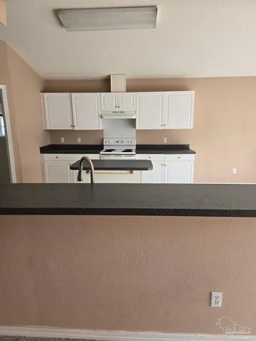 a kitchen with a sink a stove and white cabinets