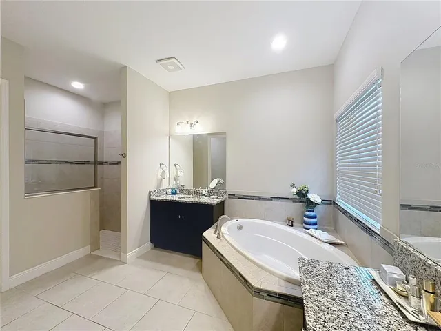 a bathroom with a granite countertop sink mirror vanity bathtub and toilet