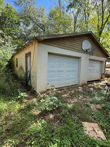 a backyard of a house with plants and garage