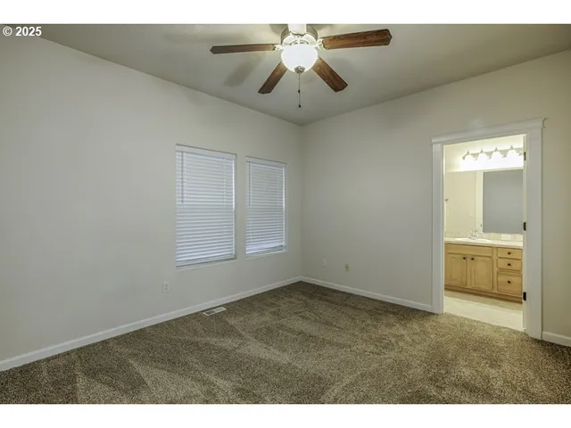 a view of an empty room and window with a ceiling fan