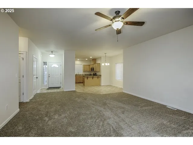 a view of an empty room and kitchen view