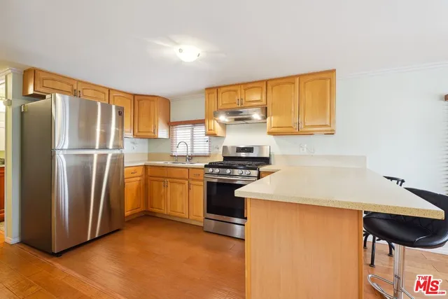 a kitchen with stainless steel appliances granite countertop a refrigerator a stove and a sink with wooden floor