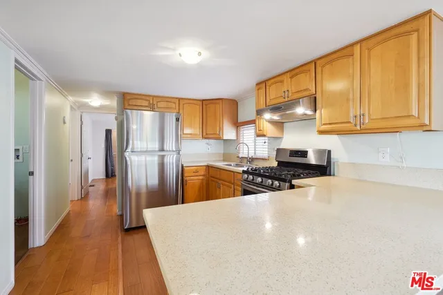 a kitchen with stainless steel appliances a refrigerator a sink a stove and wooden cabinets