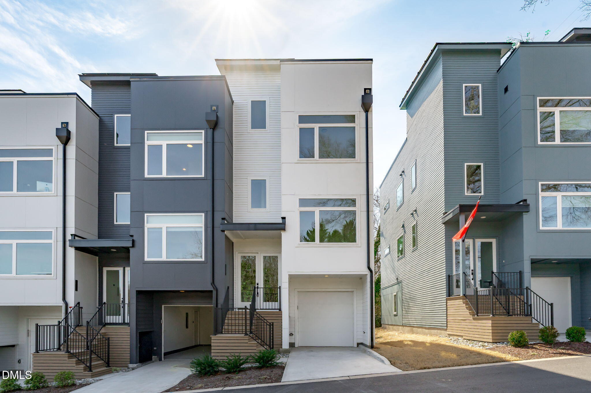 a front view of a building with glass windows and plants