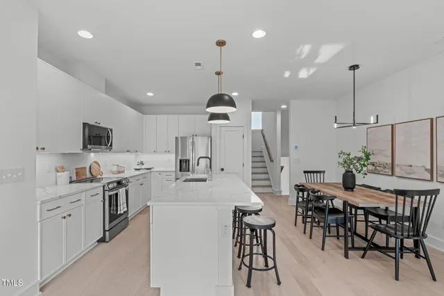 a kitchen with kitchen island a dining table chairs stainless steel appliances and cabinets