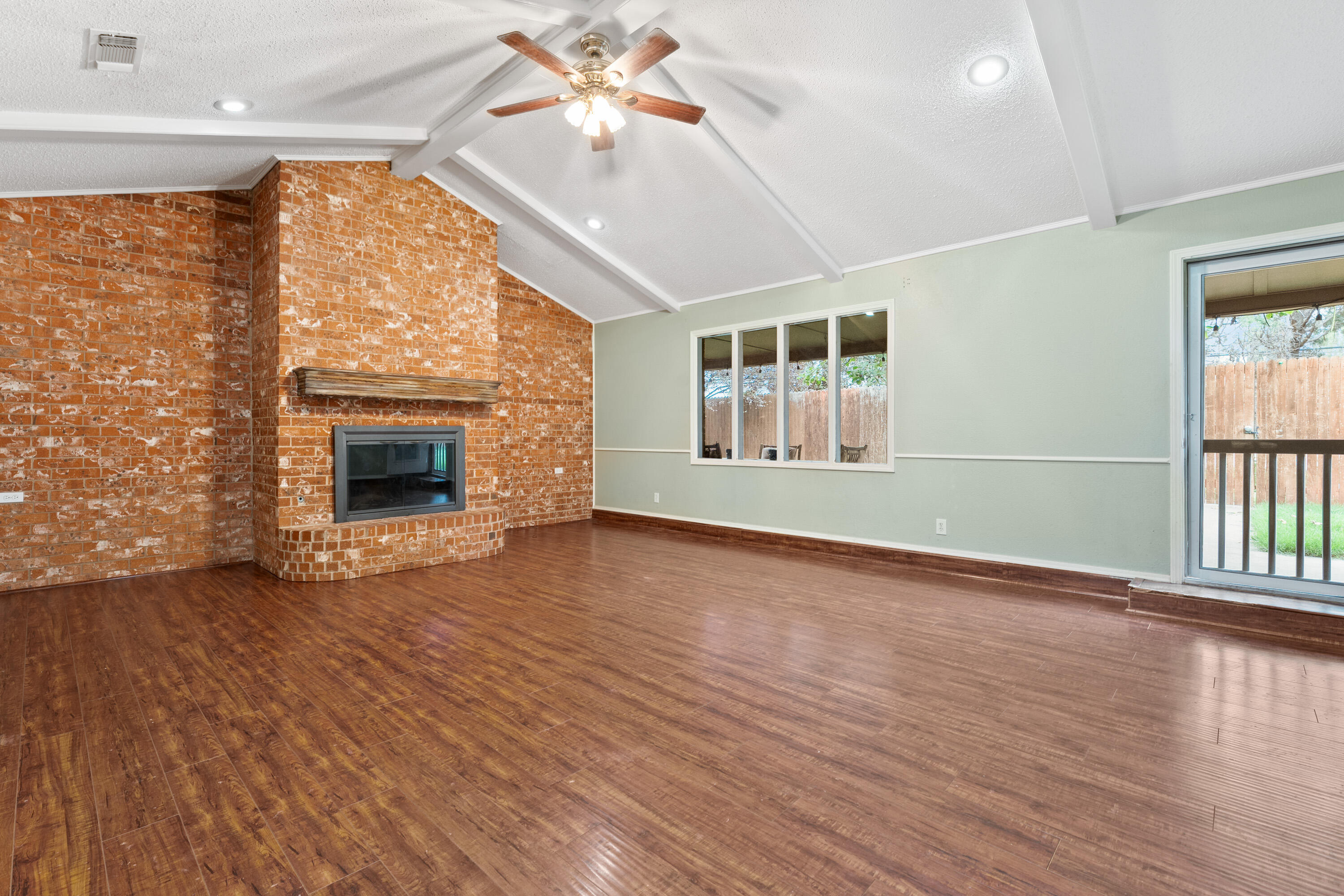 4403 78th Street Lubbock, TX 79424 - Photo 10 of 29 an empty room with wooden floor fireplace and windows