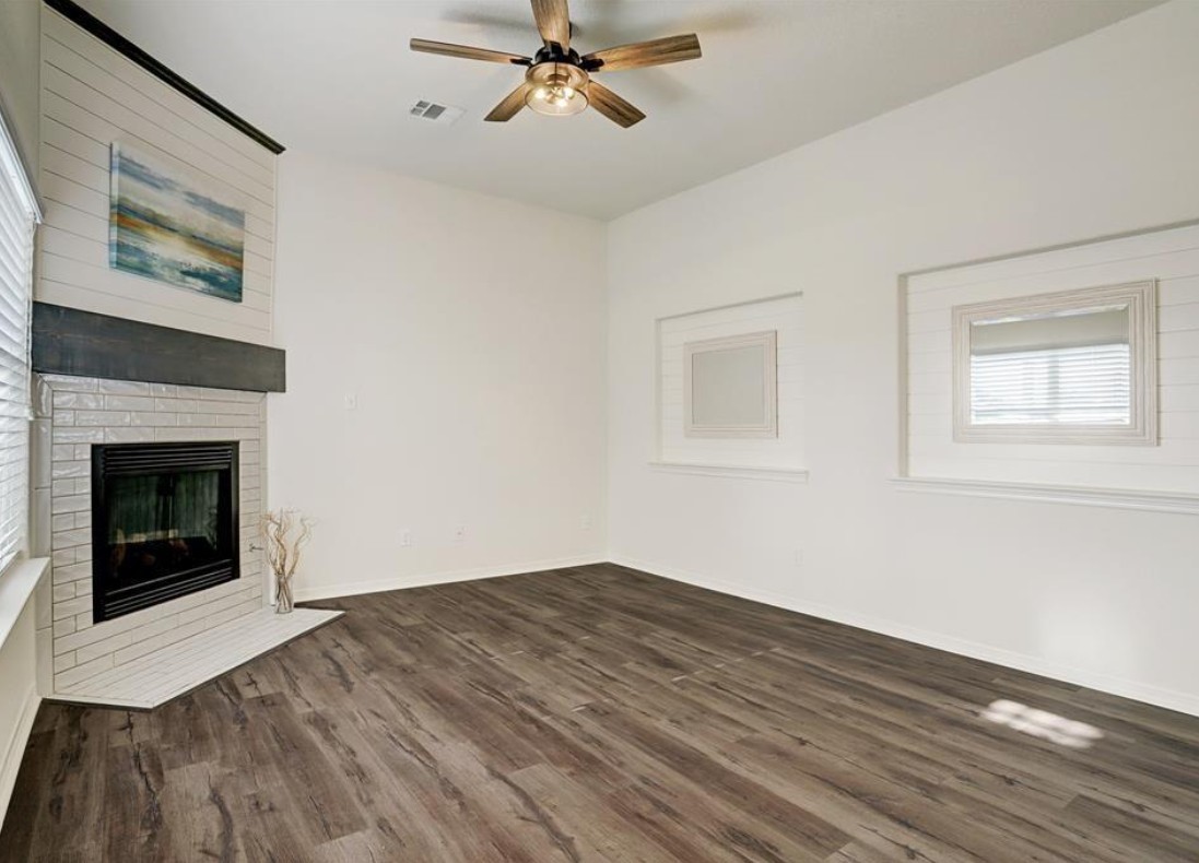 277 Capetown Conroe, TX 77356 - Photo 5 of 10 Bright and airy living room featuring soaring ceilings, a cozy fireplace, and beautiful wood-look flooring—creating the perfect space to relax and entertain.