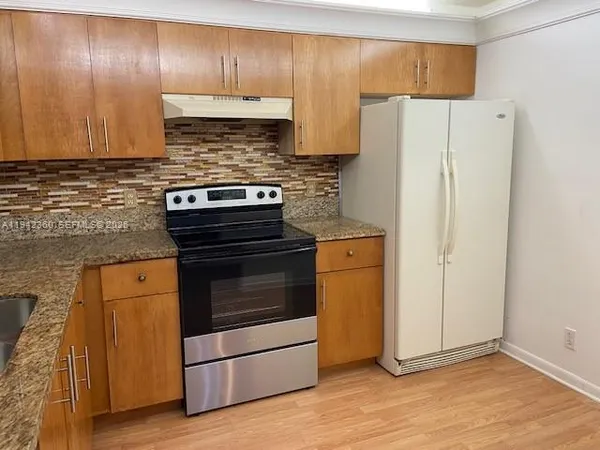 a kitchen with granite countertop wooden cabinets and a stainless steel refrigerator stove