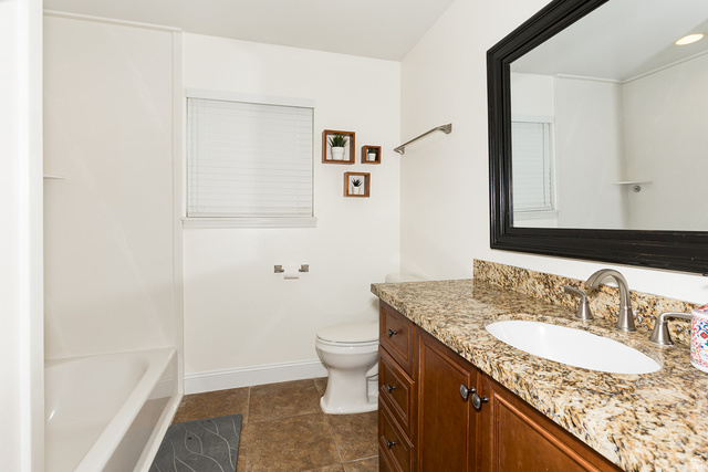 7797 North Windhover Road Eagle Mountain, UT 84005 - Photo 18 of 33 Bathroom vanity with stone countertop, undermount sink, and wood-finish cabinetry