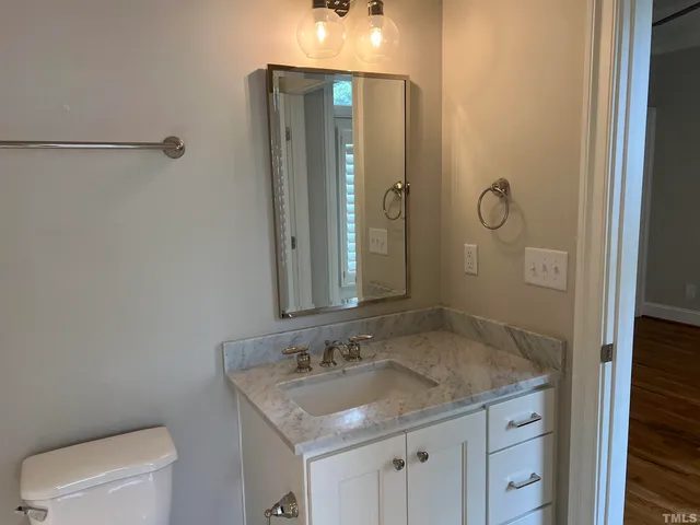 a bathroom with a granite countertop sink a toilet and shower