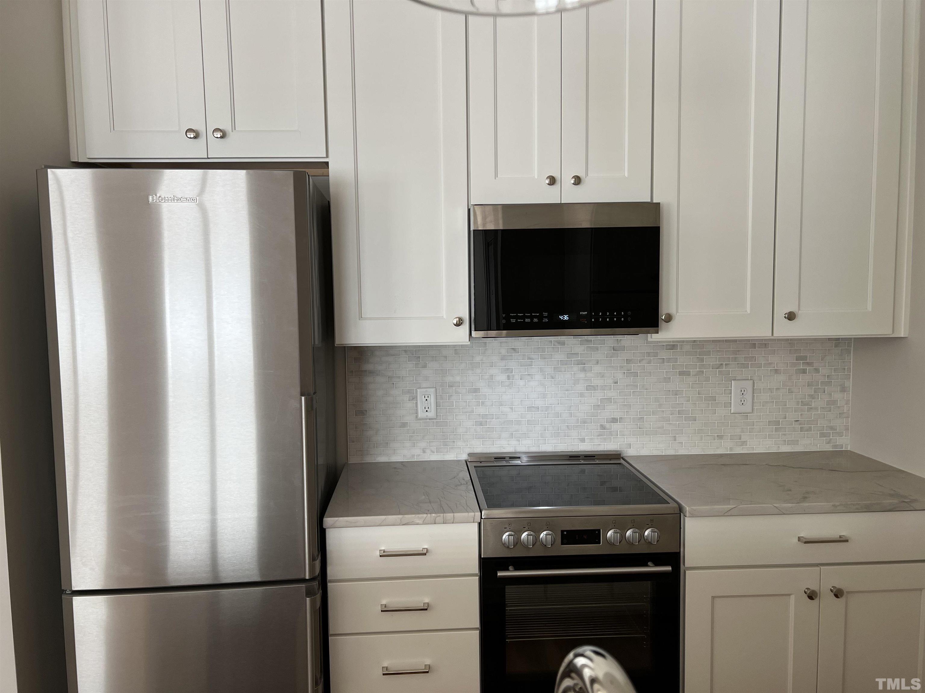 604 Daniels Street, Unit C Raleigh, NC 27605 - Photo 29 of 34 a kitchen with stainless steel appliances white cabinets and a refrigerator
