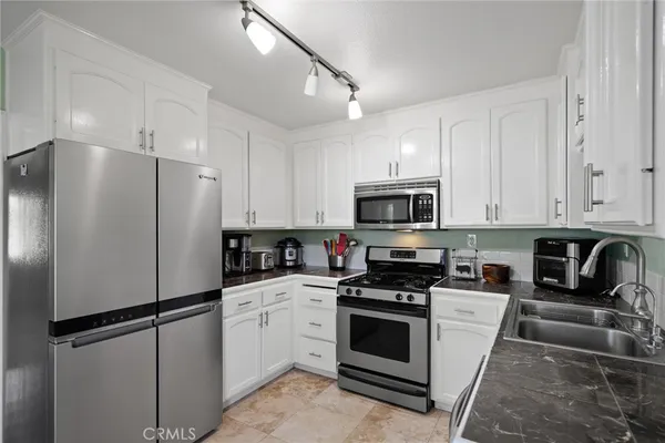 a kitchen with cabinets stainless steel appliances and sink