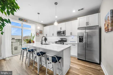 a kitchen with stainless steel appliances kitchen island granite countertop a table chairs and a refrigerator