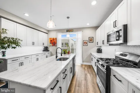 a kitchen with stainless steel appliances kitchen island granite countertop a lot of counter space and wooden floors