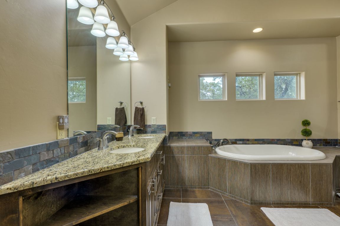 600 Mountain Dew Road Horseshoe Bay, TX 78657 - Photo 21 of 38 a bathroom with a granite countertop sink a toilet and a mirror