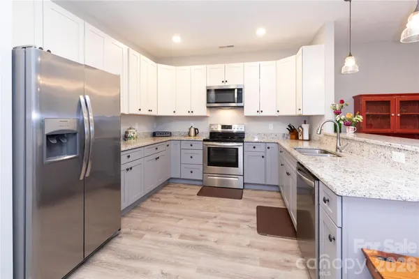 a kitchen with stainless steel appliances granite countertop a sink stove refrigerator and cabinets