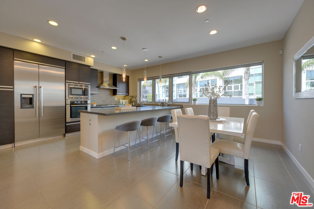 310 Washington Boulevard, Unit 802 Marina del Rey, CA 90292 - Photo 7 of 43 a kitchen with stainless steel appliances granite countertop a table chairs refrigerator and a sink