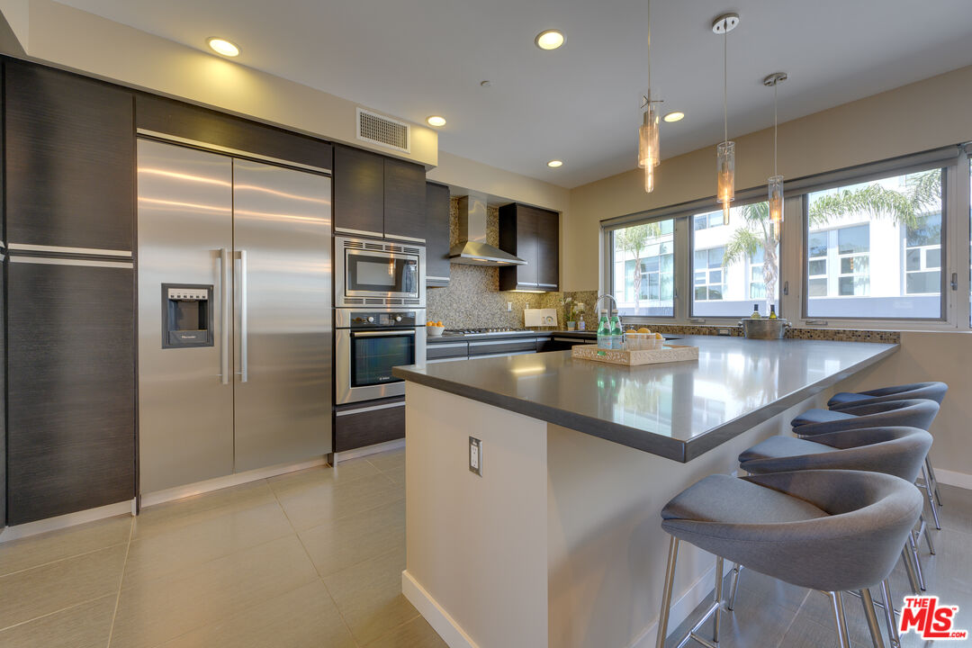 310 Washington Boulevard, Unit 802 Marina del Rey, CA 90292 - Photo 8 of 43 a large kitchen with granite countertop a large counter top stainless steel appliances and a large window