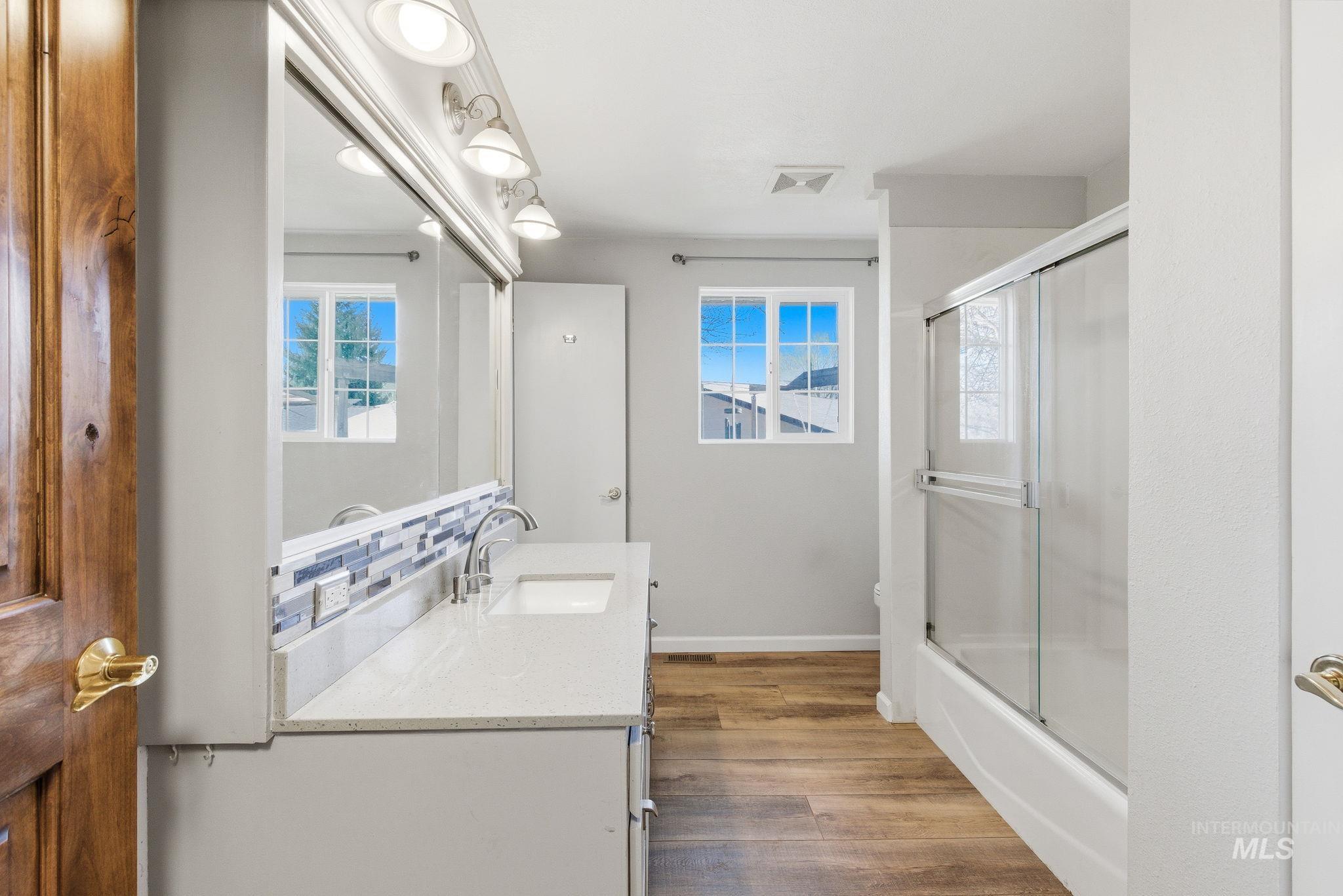 2072 South Crystal Way Boise, ID 83706 - Photo 23 of 50 Bathroom featuring vanity, dark wood-style floors, combined bath / shower with glass door, and plenty of natural light