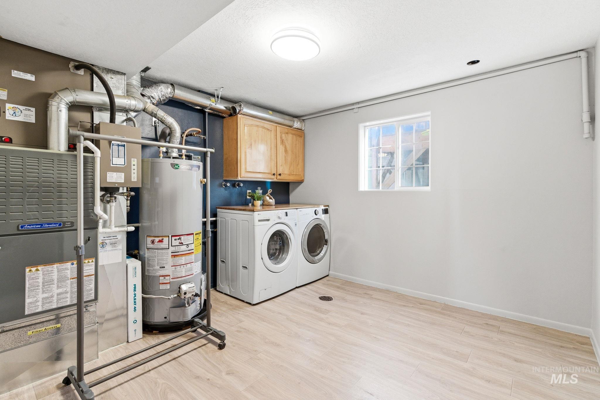 2072 South Crystal Way Boise, ID 83706 - Photo 42 of 50 Laundry area featuring light wood finished floors, cabinet space, gas water heater, washing machine and clothes dryer, and heating unit